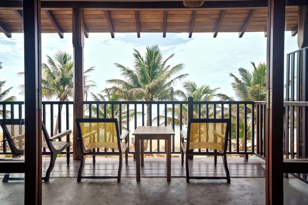 Balcony with two chairs and a table looking out through the palms