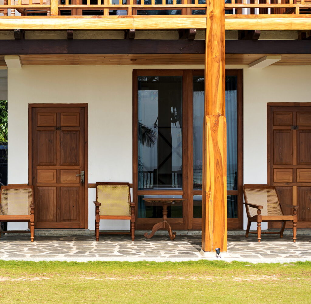 Ground-floor rooms with teak doors and chairs opening onto the lawn