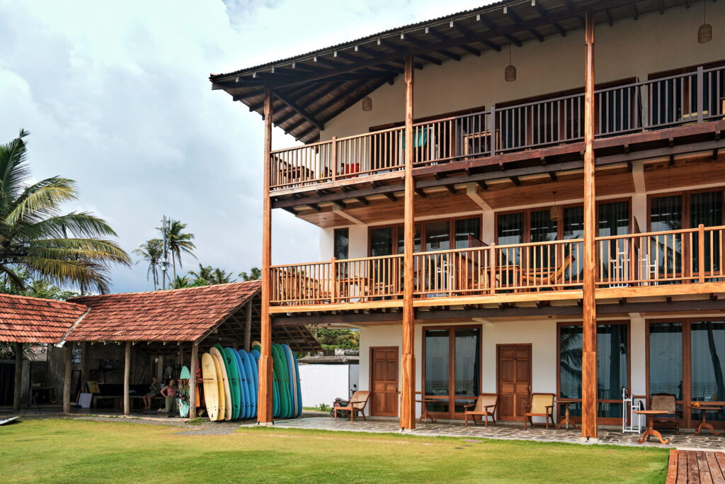 The three-storey hotel with timber balconies, palms and lawn