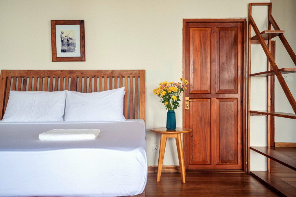 Guest room with a white bed, a teak door and fresh flowers