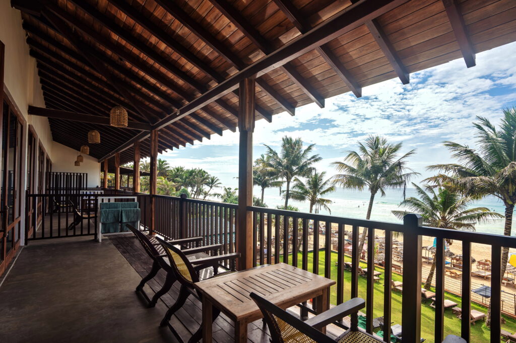 Timber veranda on the upper floor, looking over the palms to the sea
